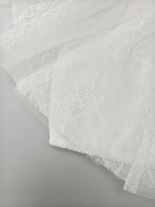 Detailed macro view of white layered lace fabric with intricate floral crochet patterns