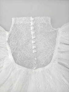 Close-up of white lace high collar with small buttons and sheer mesh splicing details