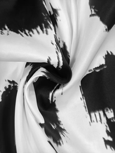 Macro detail of silky black and white abstract print fabric with smooth satin texture