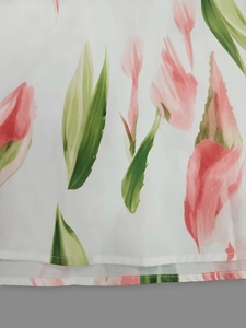 Detailed close-up of white chiffon fabric featuring pink floral prints and fine hem stitching