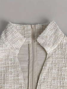 Detail of elegant beige tweed dress showing textured weave fabric and back zipper closure