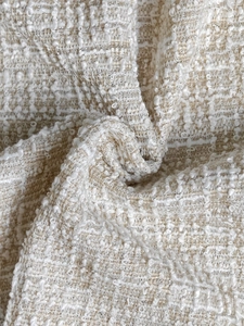Close-up of elegant cream tweed bouclé fabric with textured weave and subtle sequins