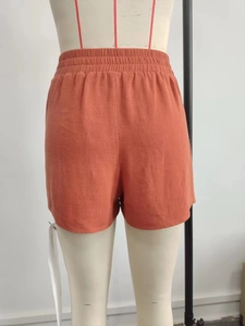 Detail of orange linen shorts with wide elastic waistband on a fashion mannequin