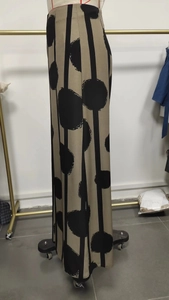Detail of bohemian khaki wide-leg pants with black vertical stripes and artistic polka dots