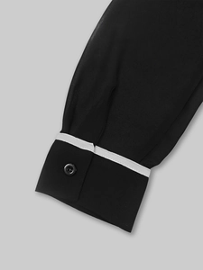 Détail du poignet à manches longues avec bordure contrastée blanche et bouton noir élégant