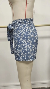 Détail de la mini-jupe fleurie bleue avec ceinture haute et motif de pétales blancs