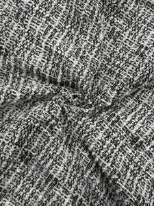 Detailed macro view of black and white bouclé tweed fabric with subtle metallic threading