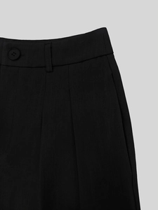 Detail view of black trousers showing button closure, pleats, and durable twill fabric texture