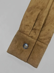 Détail du poignet en suédine caramel avec un bouton foncé en résine à quatre trous