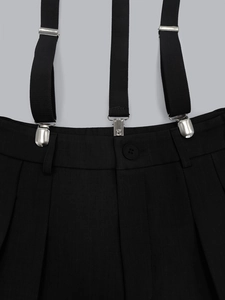 Detail of black suspender trousers with metallic clips and adjustable elastic straps