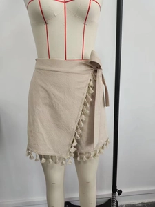 Detail of bohemian beige wrap skirt with cotton fringe tassels and side tie closure