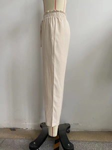 Detail of high waisted cream beach pants featuring smocked waist and drawstring tie