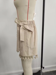 Detail view of beige cotton linen mini skirt with side bow tie and tassel hem detail