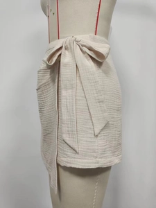 Close-up of beige high-waist wrap skirt with textured fabric and side bow detail