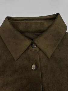 Détail macro du tissu en daim vert olive et des boutons marbrés sur une robe vintage