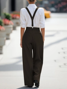 Outdoor street style view showing the back of high waisted wide leg trousers with Y-back suspenders