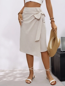 Detail of beige wrap skirt featuring side bow tie and elegant high waist texture