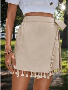 Detail of bohemian beige wrap skirt featuring fringed edges and textured cotton fabric