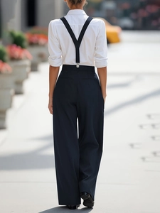 Macro view of adjustable Y-back suspenders attached to black wide-leg suit trousers