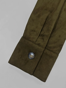 Gros plan du poignet en suédine vert olive avec un bouton aux reflets nacrés