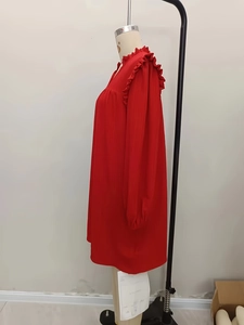 Detail of red long sleeve dress with ruffled stand collar and pleated texture fabric