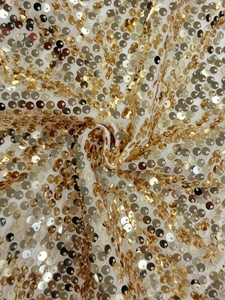 Detailed macro view of golden sequins on white mesh fabric for party clothing fashion