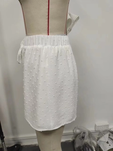 Détail de la texture en tissu Swiss Dot blanc et de la taille haute élastique de la minijupe