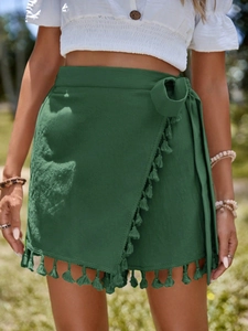 Detail of dark green wrap skirt showing cotton fabric texture and tassel trim hemline