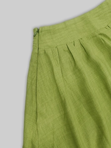 Détail d'une jupe en lin vert montrant la taille haute et la fermeture éclair latérale