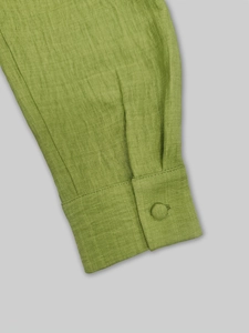 Détail de la manche d'un pull vert avec bouton recouvert de tissu et maille côtelée
