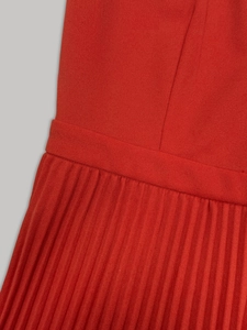 Détail de la robe rouge plissée à taille haute avec textures fines en tissu mousseline