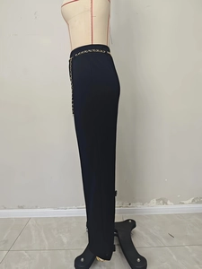 Detailed view of black high-waisted dress pants with an elegant gold metal chain belt