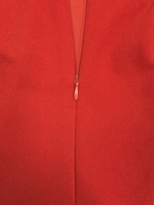 Gros plan sur la fermeture éclair invisible rouge d'une robe plissée à texture tricotée