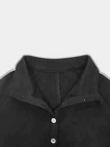 Close-up of lapel collar with white buttons and stripe detail on black sweatshirt dress