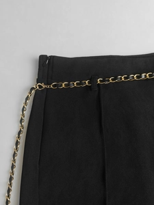 Close-up of black high-waisted trousers with an elegant woven gold chain belt and hidden zipper