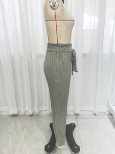 Detail of high waisted olive green trousers with ruffle elastic waist and pleated fabric