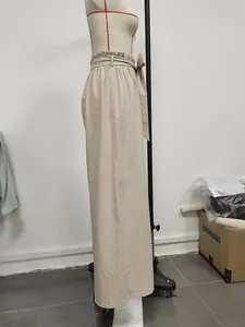 Detail of high waisted wide leg beige trousers featuring adjustable waist tie and fabric texture