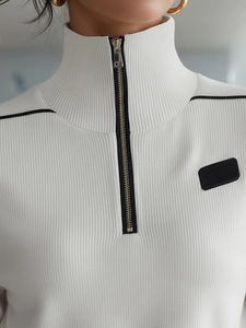 Détail du sweat-shirt en tricot côtelé blanc avec col zippé et empiècement noir