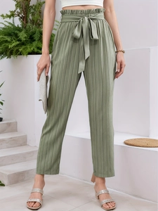Detail of olive green high-waisted trousers with pleated texture and bow waistband