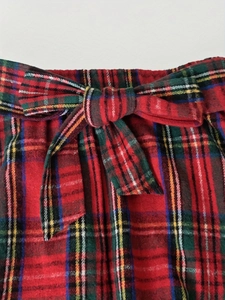 Détail de mini-jupe écossaise rouge avec taille élastique à volants et nœud de serrage