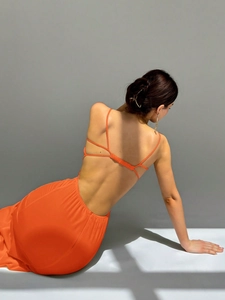 Detailed back view of a vibrant orange backless evening gown with thin straps and ruching