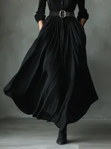 Detail of black pleated shirt dress showing textured fabric and waist belt with silver buckle