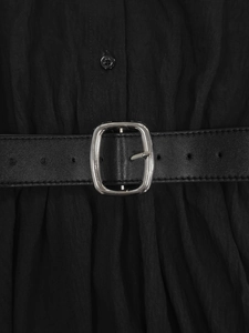 Detail of a black pleated dress showing a silver metal buckle and matching waist belt