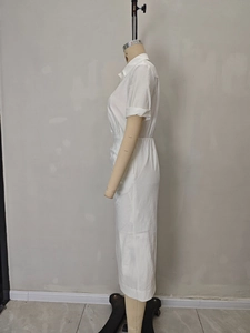 Detail of white pleated shirtdress showing textured fabric and cuffed short sleeves
