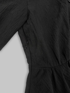 Close-up of the side invisible zipper on a black textured pleated shirt dress