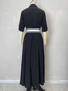 Back view of a long-sleeved black dress featuring a striped waistband and A-line skirt