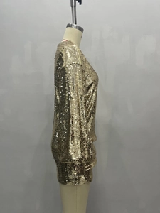 Detailed side view of loose-fit golden sequin dress with long puff sleeves and metallic shine
