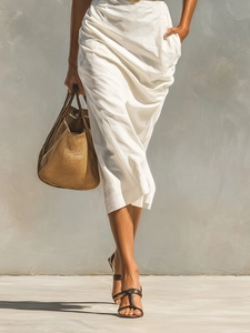 Detail of elegant white satin dress with waist pleats and brown woven tote bag