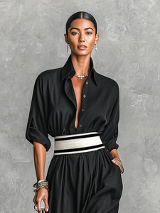 Detail of elegant black long-sleeve dress featuring a bold striped belt and floral necklace