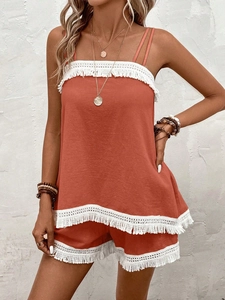 Close-up of bohemian orange crop top and shorts set with decorative white tassel trim